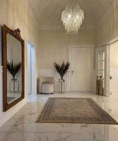 a hallway with a chandelier, mirror and vases on the floor in front of it