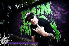 a young man pointing at the camera in front of a graffiti wall