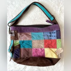 a multicolored purse sitting on top of a white blanket next to a tag