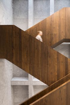 a person is walking down the stairs in a building with concrete walls and wooden floors