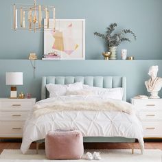 a bedroom with blue walls, white bedding and gold accessories on the nightstands