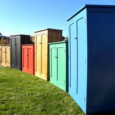 a row of multicolored storage sheds sitting in the grass