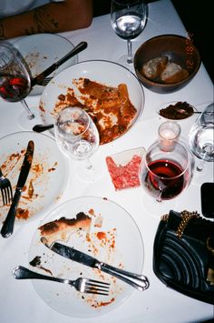 the table is full of dirty dishes and empty wine glasses