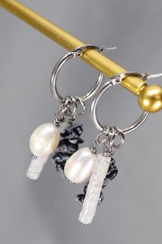 Discover the perfect blend of sophistication and boldness with these unique pin hoop earrings from Estibela. Handcrafted from durable stainless steel, these earrings feature a lustrous freshwater baroque pearl bead, a vibrant quartz bead, and a natural stone bead with an irregular shape. Designed in a boho style with subtle ethnic and vintage influences, they’re ideal for creating relaxed, expressive looks. Perfect for everyday wear, summer outings, or casual gatherings, they pair beautifully with light dresses, sundresses, and casual outfits. 
#BohoEarrings #HandcraftedJewelry #UniqueDesign #FreshwaterPearl #QuartzBead #EthnicStyle #VintageInspired #StatementJewelry #HandmadeAccessories #JewelryGift #BohoChic #FashionJewelry #EcoFriendly #ArtisanJewelry Handmade Small Hoop Pearl Earrings, Metal Dangle Hoop Earrings With Pearl Charm, Handmade Pearl Dangle Hoop Earrings, Pearl Charm Dangle Hoop Earrings, Bohemian Dangle Earrings With Pearl Charm, Elegant Earrings With Baroque Pearl Charm, Bohemian Dangle Shell Earrings, Light Dresses, Casual Festival