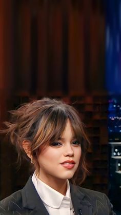 a woman in a suit and tie posing for the camera with city lights behind her