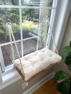 a window sill with a swing hanging from it's side, next to a potted plant