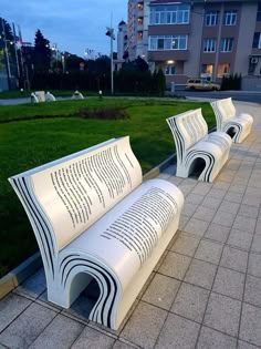 two white benches sitting on top of a sidewalk