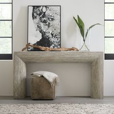 a white table with a plant and some pictures on the wall in front of it