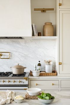 a white kitchen with marble counter tops and gold trimmings on the cabinet doors