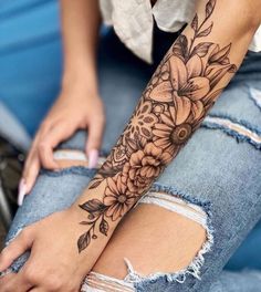 a woman's arm with flowers and leaves tattooed on the side of her leg