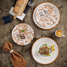 three plates with different designs on them sitting on a table next to utensils