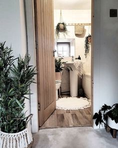 an open door leading to a bathroom with potted plants