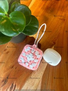 a crocheted square ornament next to a computer mouse on a wooden table