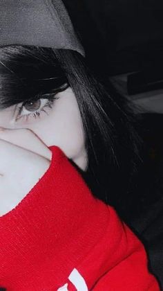 a girl with black hair wearing a red shirt and a baseball cap covering her face