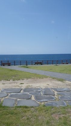 there is a bench on the grass by the water and in the distance are benches