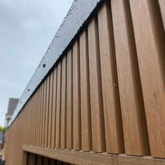 raindrops on the side of a wooden fence near a building with brown siding