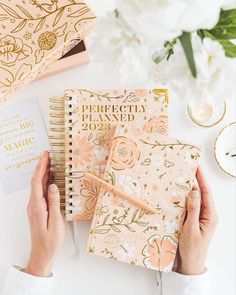 a person holding a planner next to some flowers