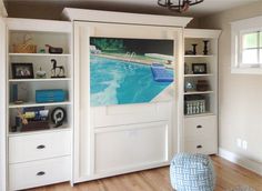 a living room with white bookcases and a swimming pool mural on the wall