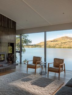 a living room with two chairs and a fire place in front of a large window