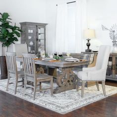 a dining room table and chairs with a rug on the floor in front of it