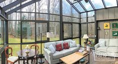 a living room filled with furniture next to a large glass wall covered in lots of windows