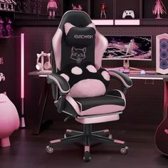 a computer chair with a black and white cat design on the back, sitting in front of a pink guitar case