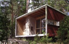 a small cabin in the woods surrounded by trees and rocks, with an open window