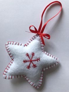 an ornament shaped like a star hanging from a red ribbon on a white surface