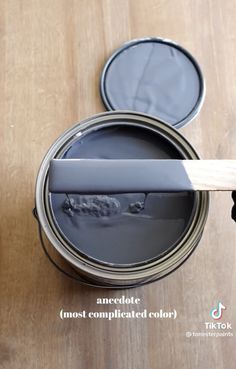 a paint can with a brush sticking out of it on top of a wooden table