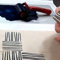 a person using scissors to cut fabric on a piece of paper with black and white stripes