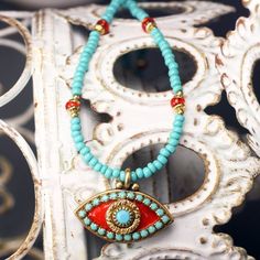 Brilliant shades of coral and turquoise pop in this summer-inspired beaded evil eye necklace by Michal Golan. Made with glass beads, enamel, brilliant Swarovski crystals, and 24K gold plating. A modern take on the classic good luck symbol. This piece looks amazing paired with a simple black top or a flowy white summer dress. A unique and eye-catching piece that will be sure to get comments and compliments every time you wear it. ................................................................... Bohemian Turquoise Beaded Bracelets With Evil Eye, Summer Evil Eye Jewelry With Round Beads, Bohemian Evil Eye Beads For The Beach, Bohemian Evil Eye Beads For Beach, Bohemian Blue Beaded Necklaces With Evil Eye, Bohemian Evil Eye Round Beads, Bohemian Turquoise Evil Eye Necklace, Bohemian Evil Eye Beads, Red Bohemian Evil Eye Jewelry