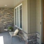 an outdoor patio with chairs and tables on it, next to a stone wall that has been built into the side of a house