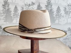 Introducing our Glazed Toyo Straw Hat with Flat Brim in Natural! This stylish hat features a beautiful Ivory and Olive 100% silk trim with an antique brass finding. Made from high-quality materials, this hat is perfect for adding a touch of style to your resort and everyday outfits. Stay cool and fashionable with this must-have accessory! One of a kind. Headsize is Medium 22 1/2" Luxury Handmade Wide Brim Hat, Cream Panama Hat With Short Brim For Country Events, Luxury Cream Hat With Short Brim, Elegant Cream Toquilla Straw Hat Band, Bohemian Cream Panama Hat With Curved Brim, Luxury Cream Flat Brim Hat, Handmade Cream Fedora With Short Brim, Handmade Cream Hat Bands With Curved Brim, Cream Bohemian Toquilla Straw Hats