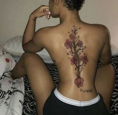 a woman sitting on top of a bed with her back turned to the camera and tattoos