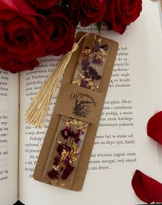 the bookmark is decorated with gold flakes and red roses next to an open book