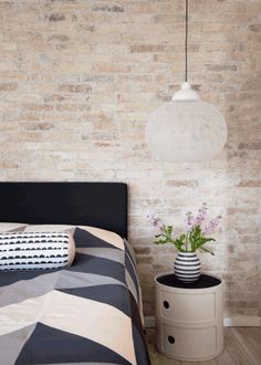 a black and white striped bed in front of a brick wall with two vases