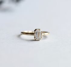 Simple and classic faceted emerald cut moissanite set on 14k yellow gold ring. Charles and Colvard moissanite stone. Comes with Forever One Charles and Colvard authenticity/warranty card Stone Shape: Emerald Metal type: 14 Karat gold Cut: Step-cut Color: GHI Carat weight: 0.5 ct Stone hardness: 9.25/10 Approx 1.6mm band width Stone size: 4mm x 6mm Radiant-Cut Moissanite: https://www.etsy.com/listing/1008204719/forever-one-radiant-emerald-cut?ref=shop_home_active_1&frs=1 Cubic Zirconia: https Emerald Cut Emerald Ring With Rose Cut Diamonds, 14k Gold Emerald Cut Solitaire Diamond Ring, 14k Gold Emerald Ring With Diamond For Wedding, 14k Gold Emerald Cut Emerald Ring With Single Diamond, Emerald Ring In 14k Yellow Gold With Square Cut, Square Cut Emerald Ring In 14k Yellow Gold, Gift Emerald Cut Ring With Single Diamond, Square Cut Emerald Ring In 14k Gold For Wedding, Octagon Emerald Ring In Yellow Gold With Brilliant Cut