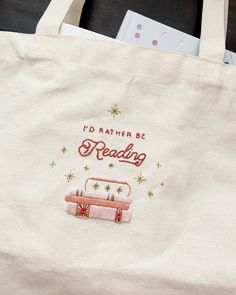 a tote bag that says i'd rather be reading next to some books