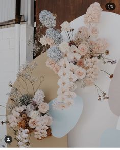 a bunch of flowers sitting on top of a wooden table next to a white wall