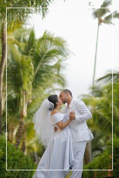 a bride and groom kissing in front of palm trees at their wedding day with a white frame around them