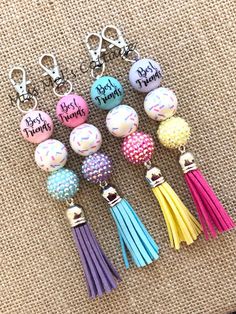 six different colored tasselled key chains with words on them