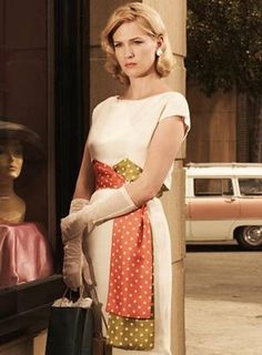 a woman standing in front of a store window with mannequins behind her