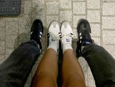 two people standing next to each other with their feet on the ground and one person wearing white shoes