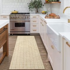 a kitchen with white cabinets and an area rug in front of the stove top oven