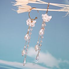 These long tassel dangle drop earrings features pearl like white flower and a long trail of artificial pearls and crystal drop earrings. These earrings make a big picture but light weight to wear, perfect wedding party earrings, bridal earrings, fashion earrings that can pair with your outfit to complete your fashion look. Materials: artificial pearls, resin, alloy, crystalFinish: gold color Jewelry Care: See more information about how to care for your jewelry here. Shipping Policy: Orders will White Dangle Crystal Earrings With Pearl Drop, Party Tassel Drop Earrings With Pearl Detail, Party Tassel Pearl Drop Earrings, White Pearl Charm Chandelier Earrings For Party, White Chandelier Earrings With Pearl Chain For Party, Elegant Flower Earrings With Dangling Beads, White Dangle Bridal Earrings With Pearl Charm, Elegant Flower Earrings With Dangling Beads For Wedding, White Dangle Tassel Earrings With Pearl Drop