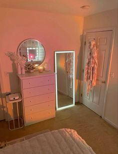 a bedroom with a dresser, mirror and lights on it's side door is shown