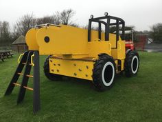 a large yellow machine sitting on top of a lush green field