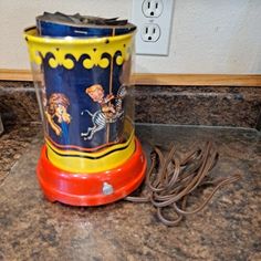 a colorful cup sitting on top of a counter next to an electrical outlet and power strip