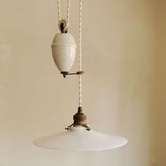 a white light hanging from a ceiling with two cords attached to the lamp and one cord connected to it