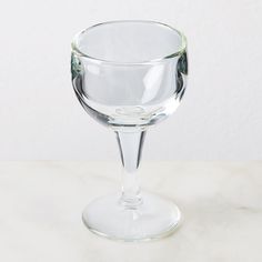 a clear wine glass sitting on top of a white countertop next to a wall